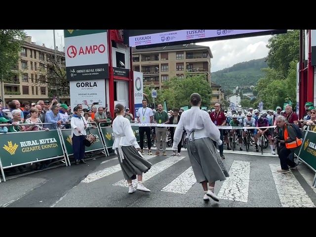 Irteera puntuan dantza egin diete txirrindulariei, eta jarraian zinta moztu dute ordezkariek. bideoaren irudi txikia
